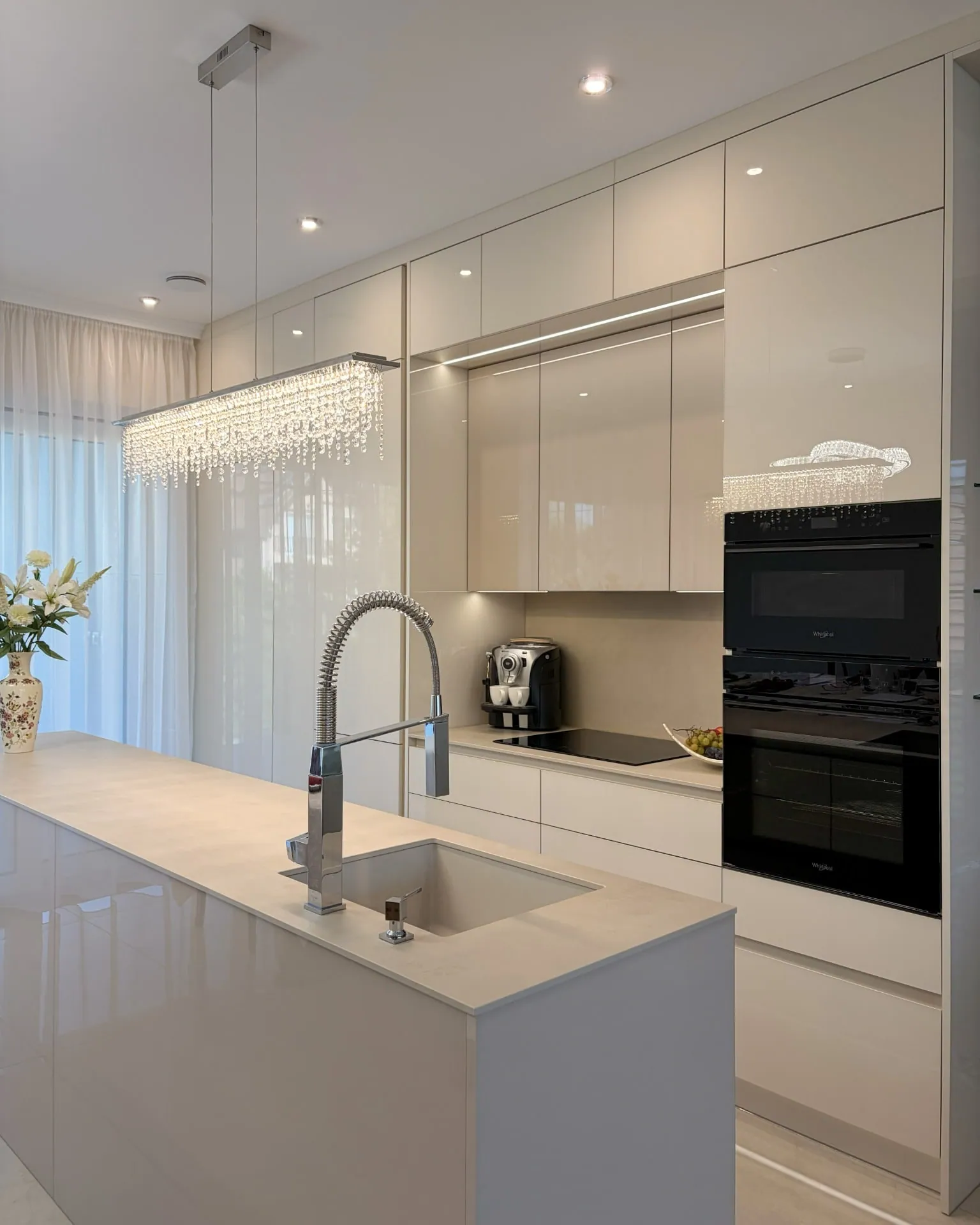 Light, high-gloss, handleless kitchen with an island and a professional tap