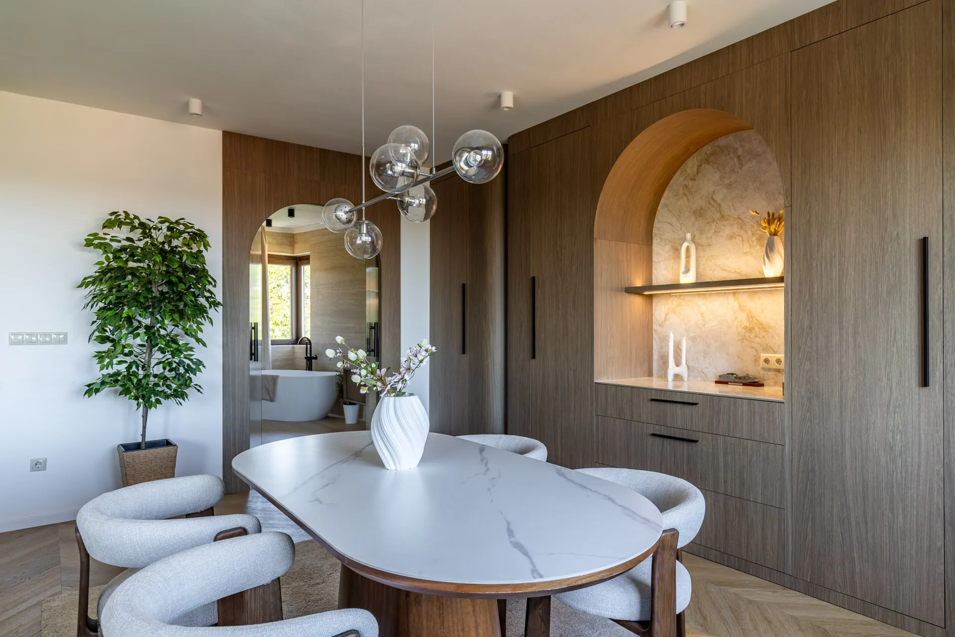 Dining area with an arched, illuminated shelf niche and a wooden furniture wall