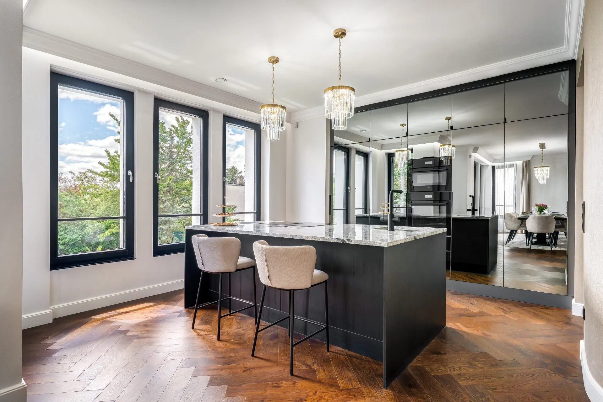 Show kitchen with a dark island, mirror-clad larder cabinets behind