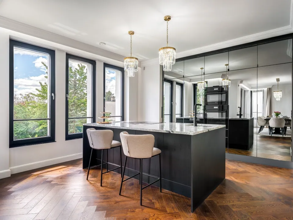 Show kitchen with a dark island, mirror-clad larder cabinets behind