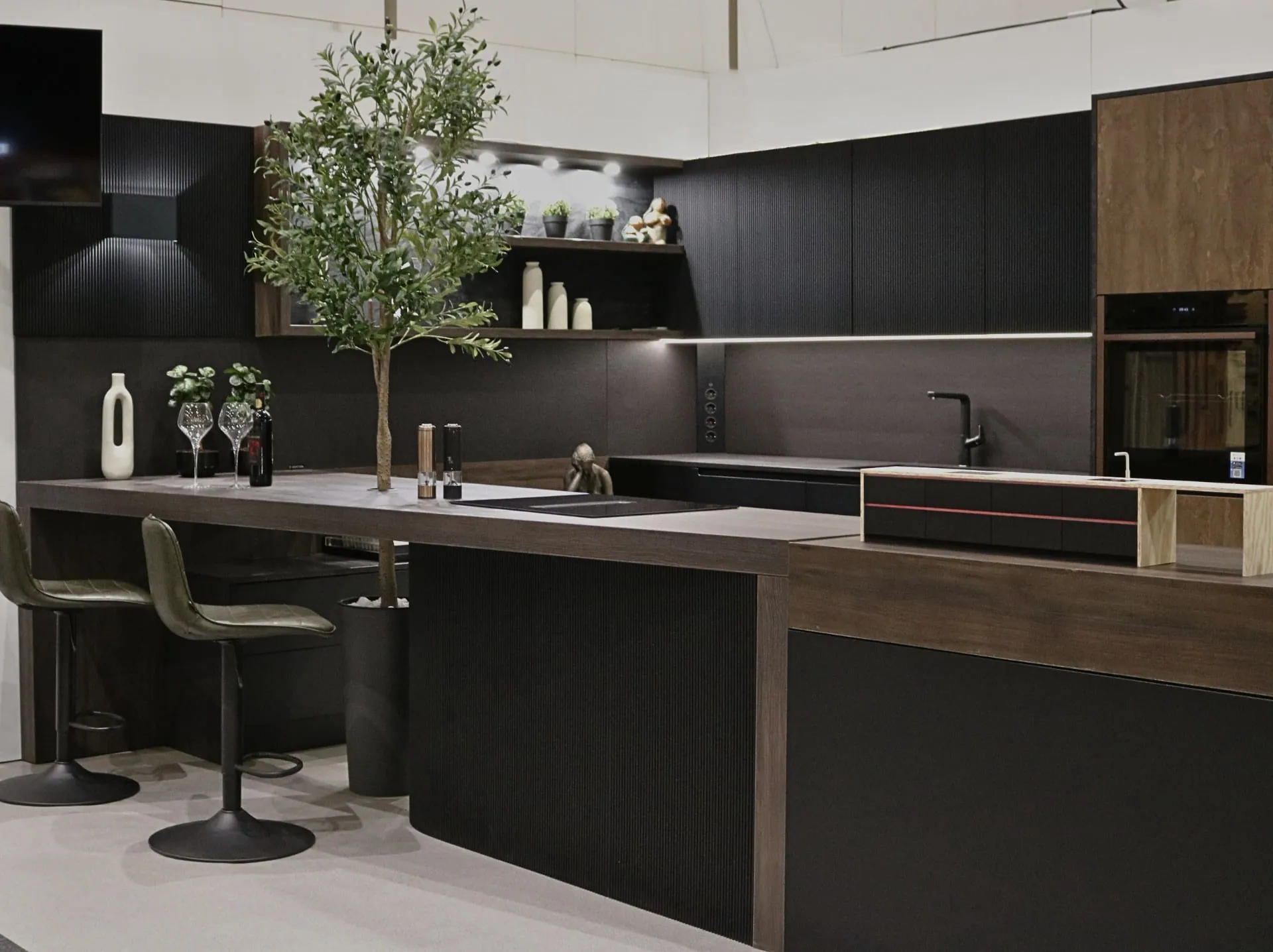 Exhibition kitchen with a height-adjustable worktop and an olive tree