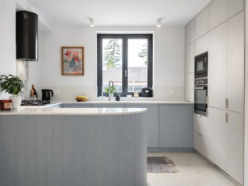 Cashmere and light blue kitchen with a curved, ribbed island