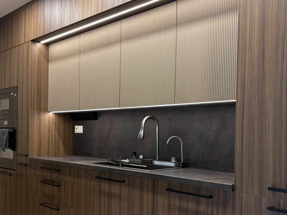 Wood-grain kitchen with ribbed wall cabinets and integrated LED lighting