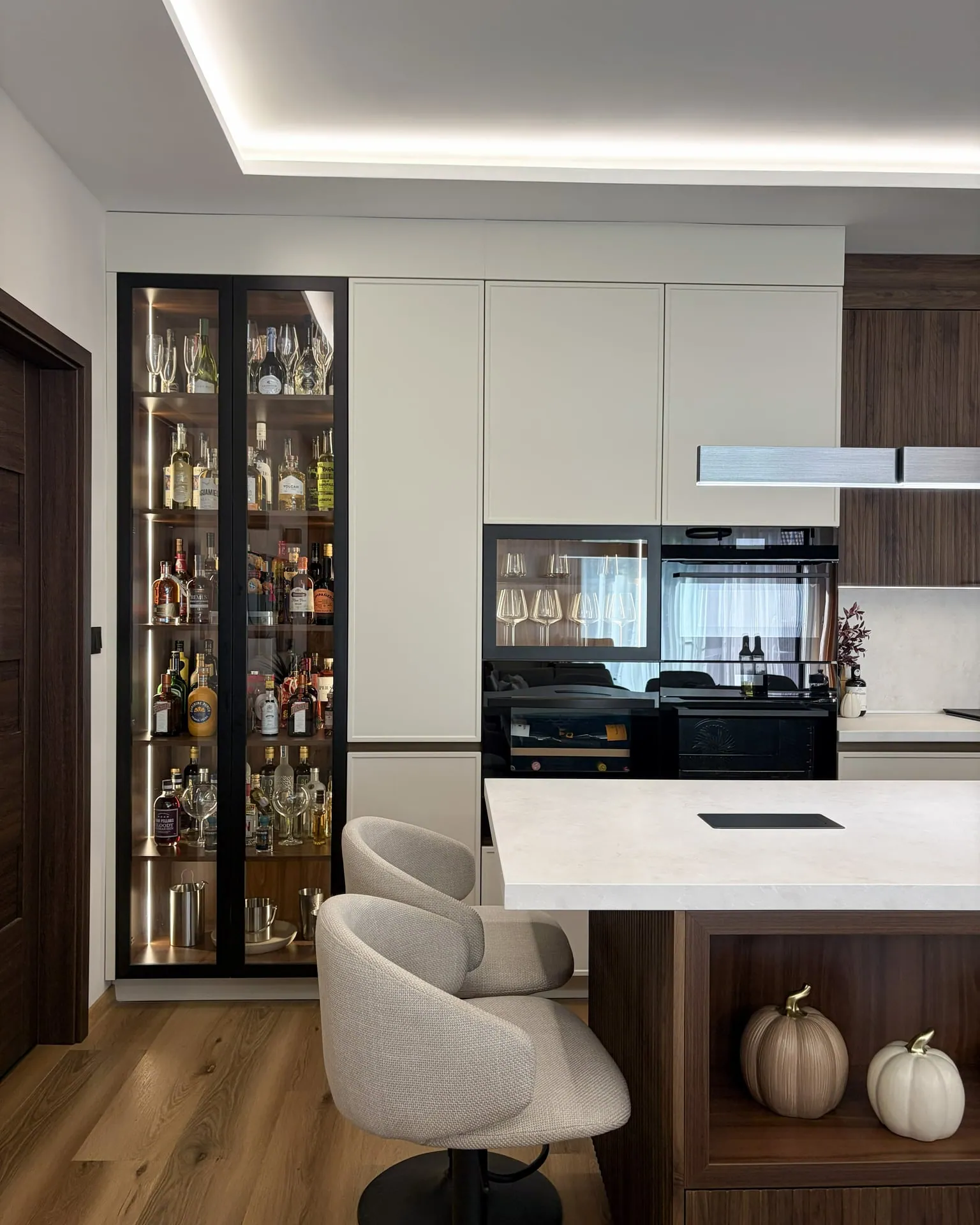 Illuminated aluminium-framed drinks cabinet and tall cabinet run with built-in appliances