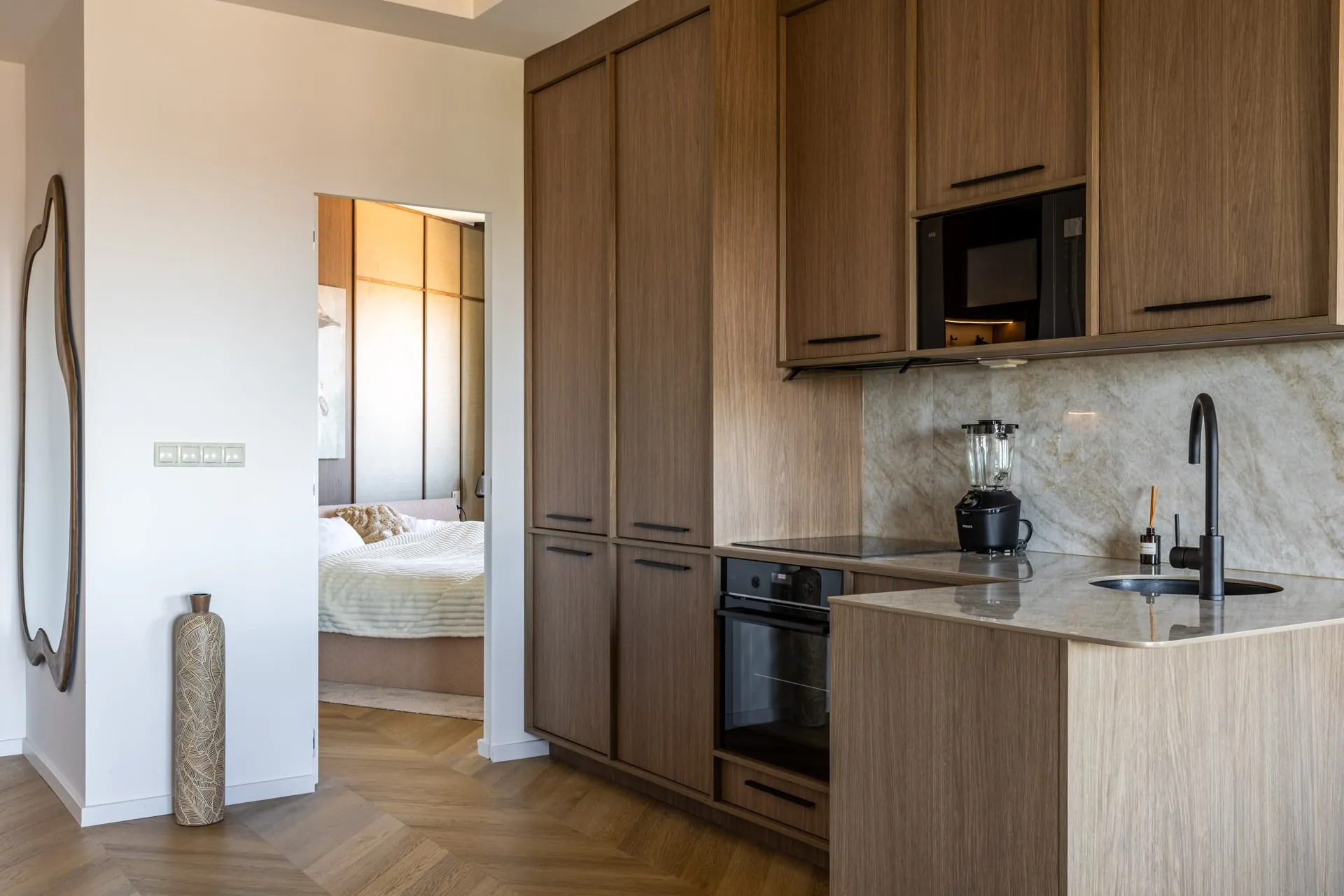 The kitchen with its stone-effect splashback, the bedroom beyond