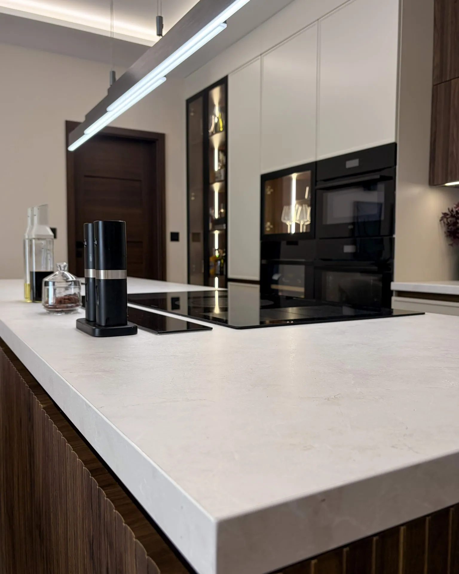 Light stone-effect worktop on the island, the tall cabinet run behind
