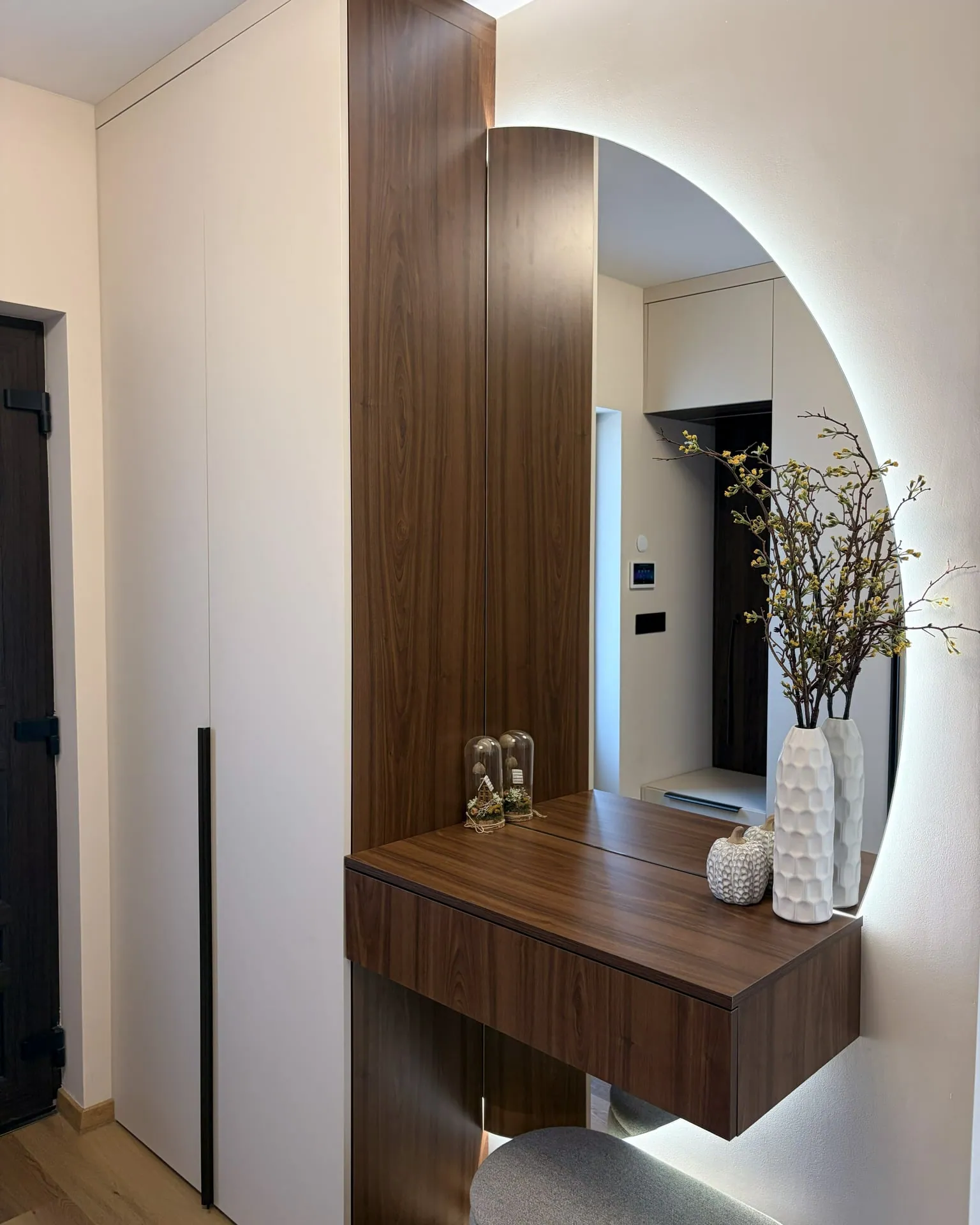 Hallway with walnut panelling and an illuminated round mirror