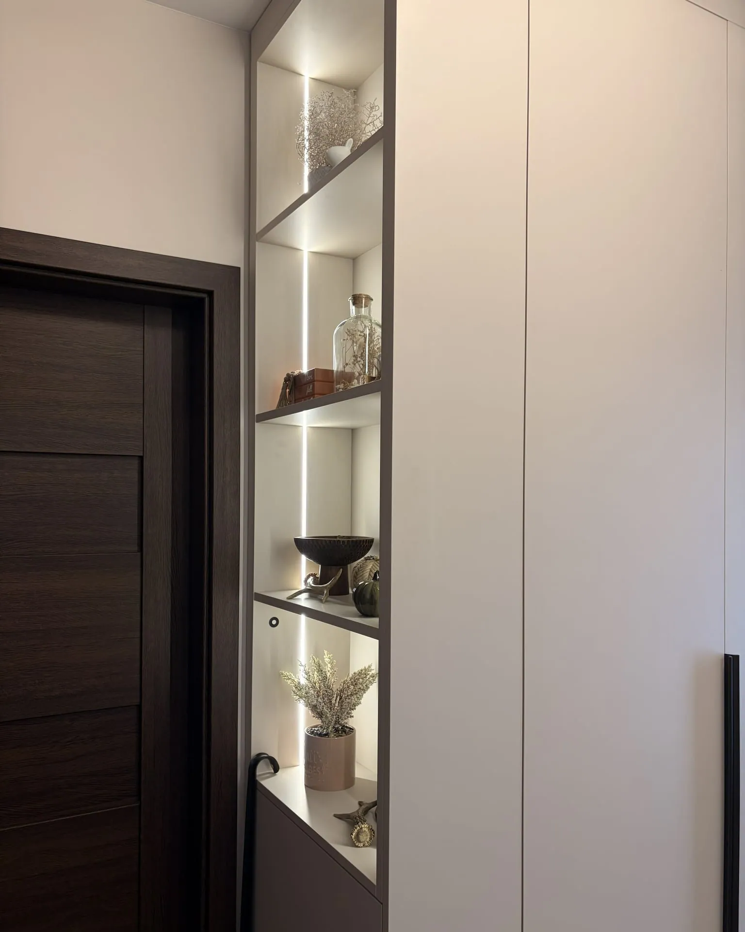 Illuminated open shelf niche next to the hallway wardrobe