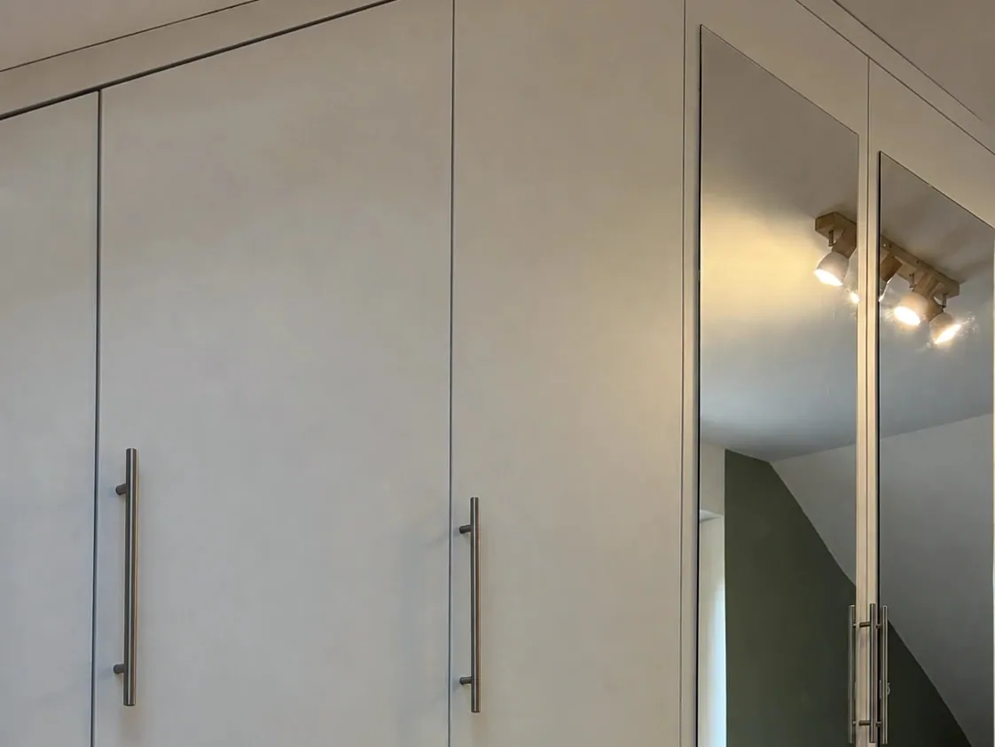 Attic built-in wardrobe fitted to the sloping ceiling, with mirrored doors